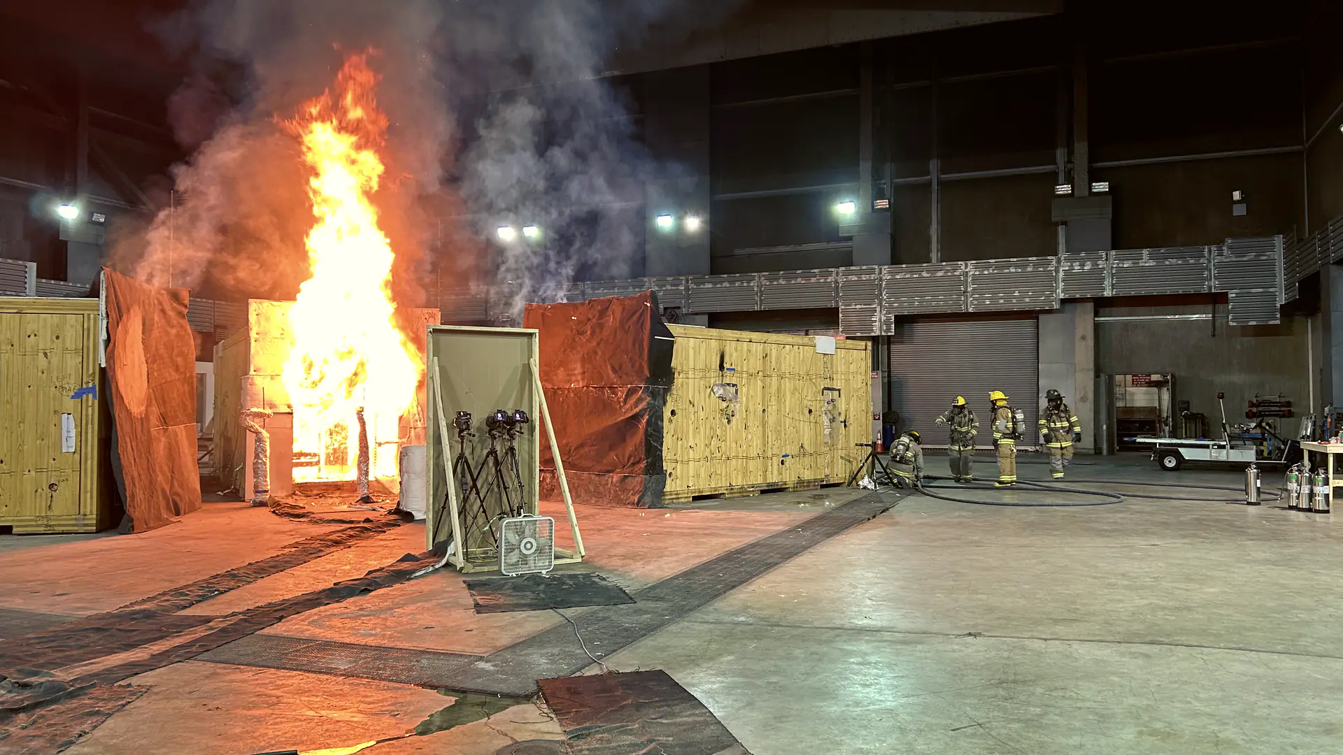 Firefighters watching a wooden building burn during a fire test